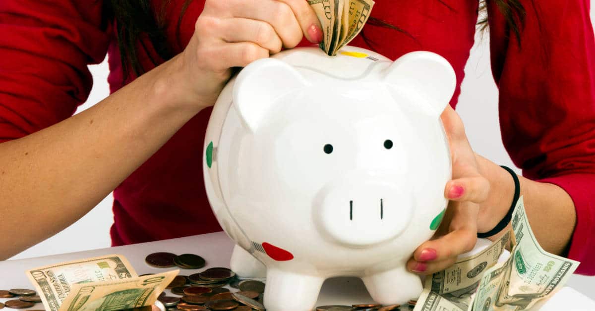 Woman putting money into savings piggy bank