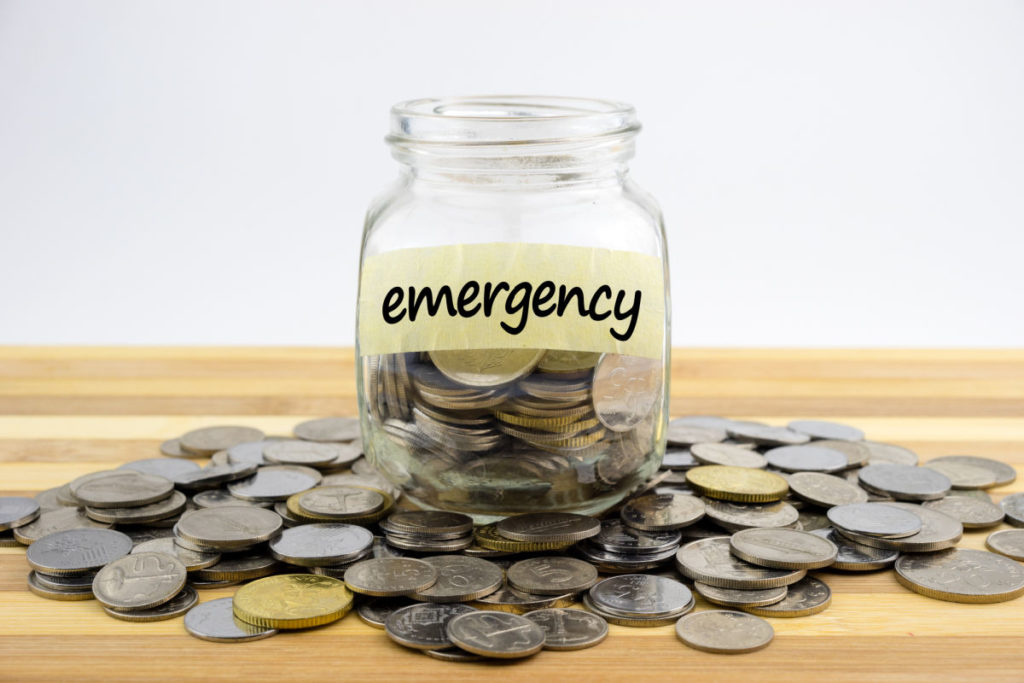 coins in a glass jar labeled emergency.