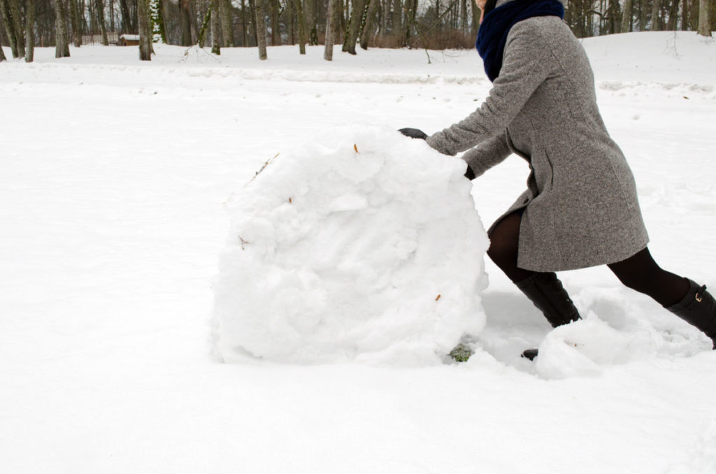 woman rolling large snowball